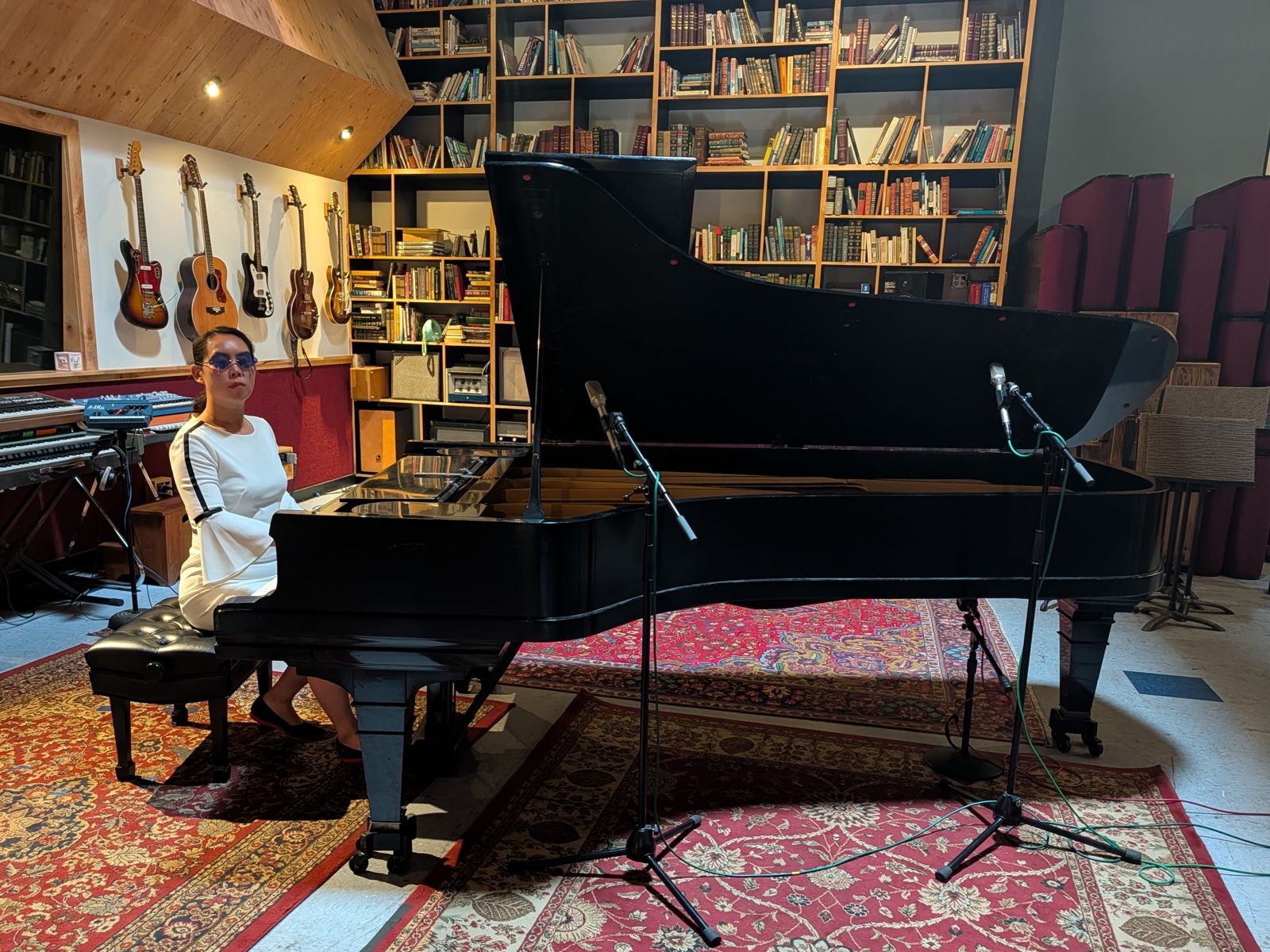 Michelle seated at the grand piano across the live room, microphones set up around it.